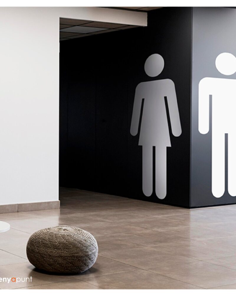 Pictogrames grans de lavabos de dona i home aplicats en vinil sobre una paret fosca