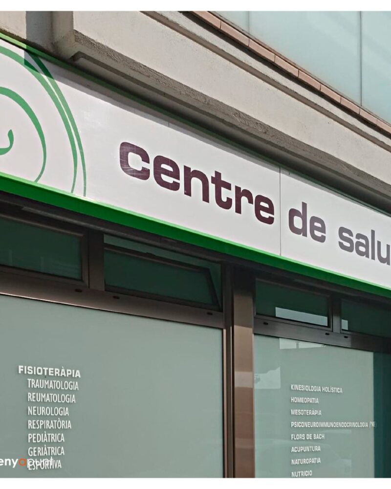Rètol de façana d'un centre de salut, amb el llistat de serveis en vinil als vidres